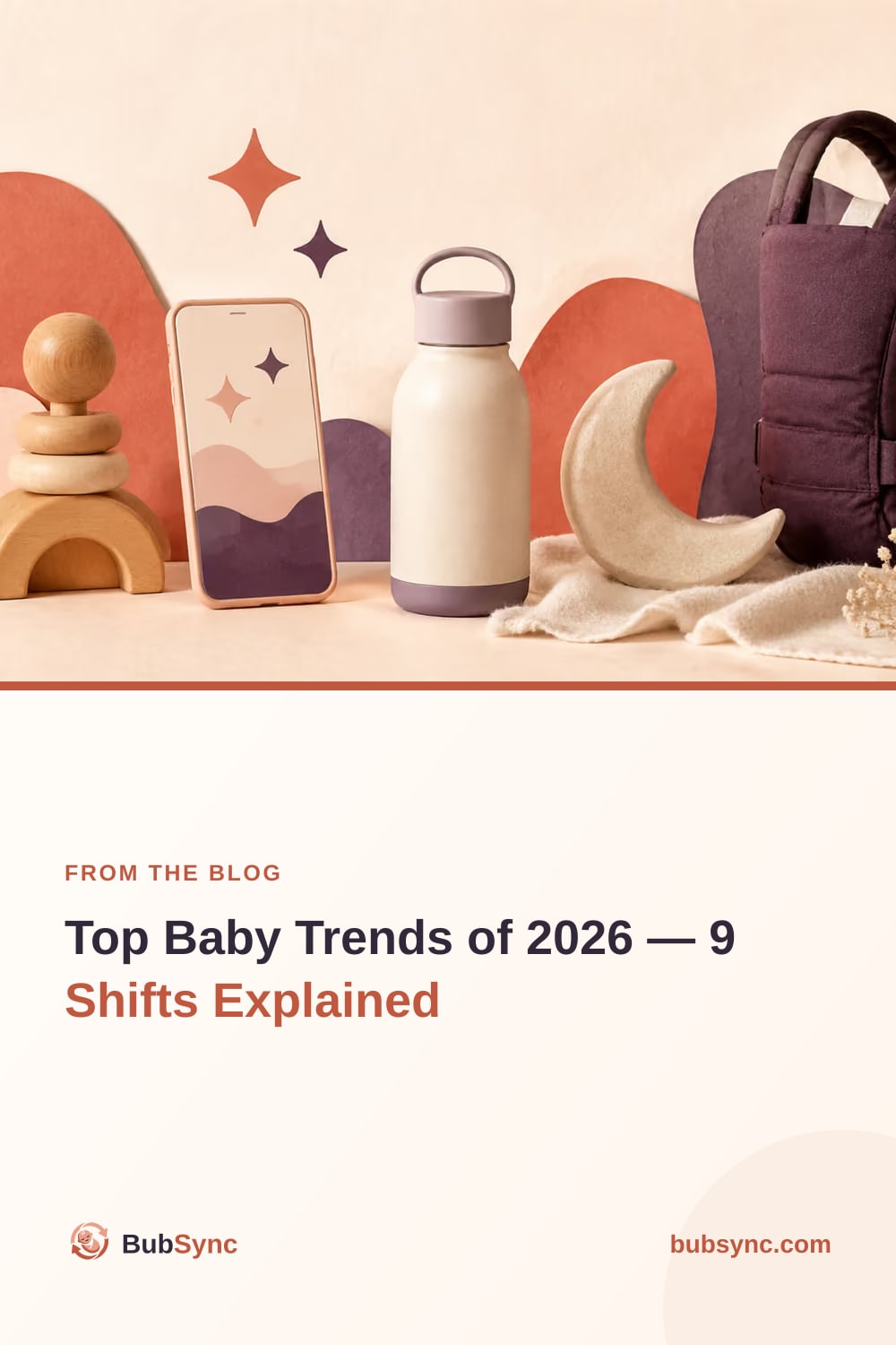 A flat-lay of 2026 baby gear — a phone, an insulated bottle, a quilted change bag and a wooden stacking toy — arranged on paper-cut hills